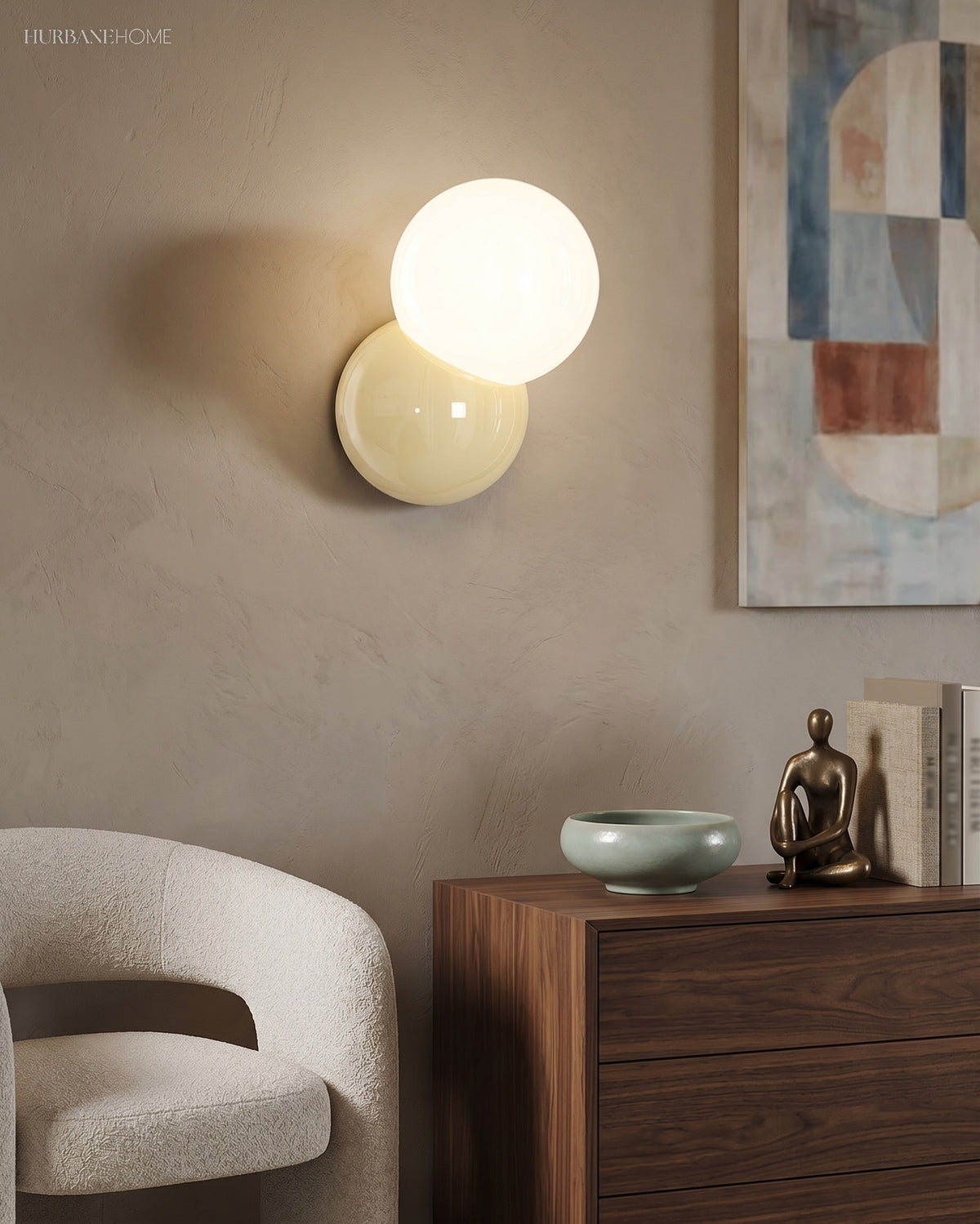 Wall sconce with an opal globe lit above a walnut sideboard and a boucle chair
