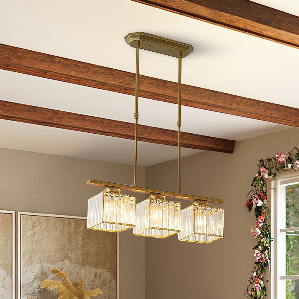 Gold three light linear pendant light under a beamed ceiling near a window
