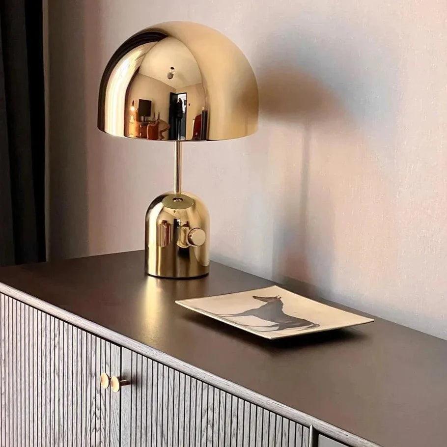 Gold dome lamp lit close on a fluted cabinet with a small dish beside it