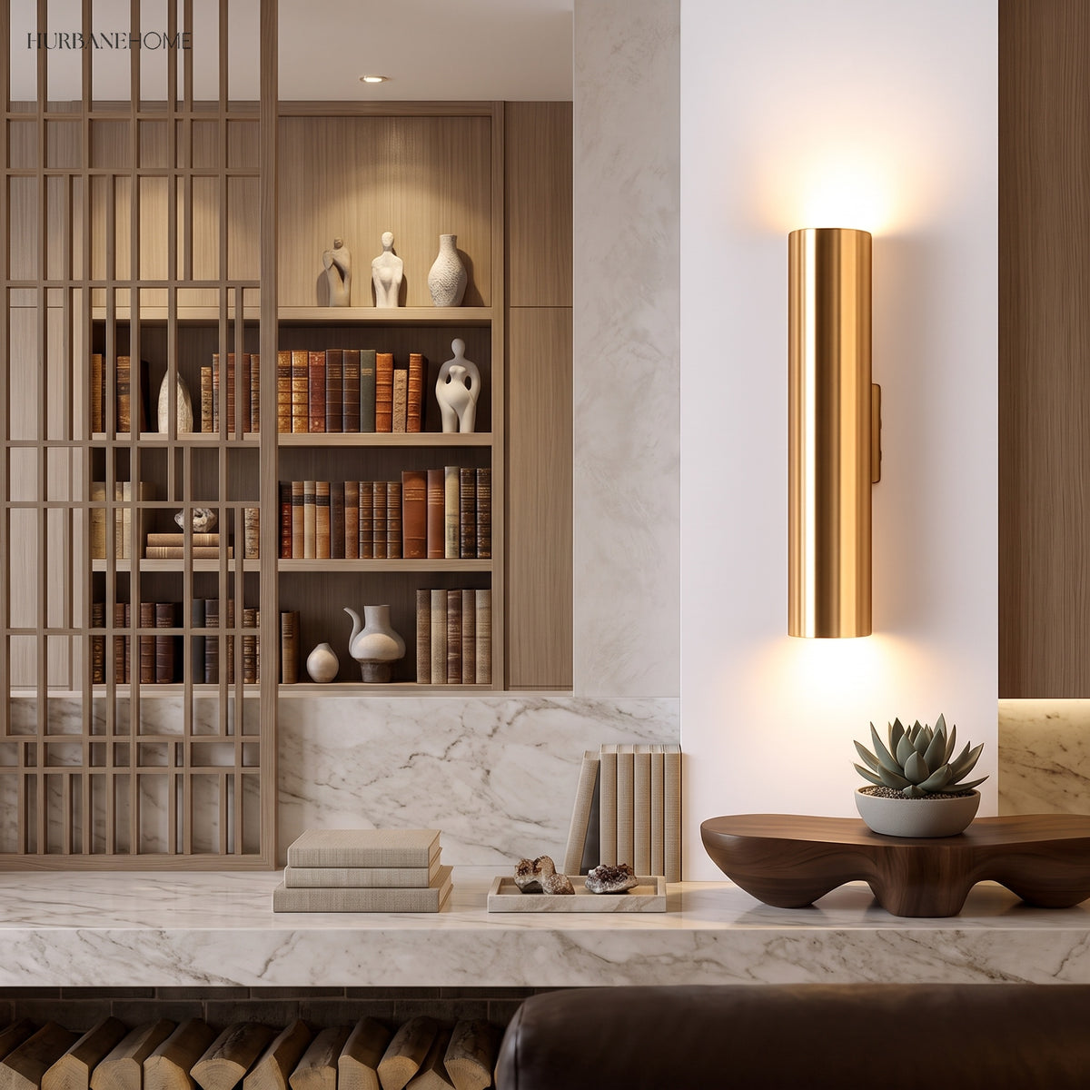 Gold tube sconce lit on a pale wall beside open shelving