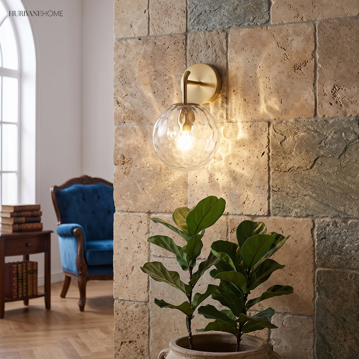 Rippled glass globe sconce lit on a stone wall beside a plant