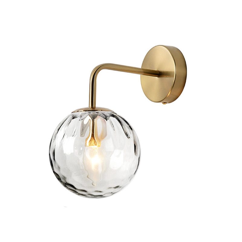 Unlit gold sconce and rippled glass globe on a plain background