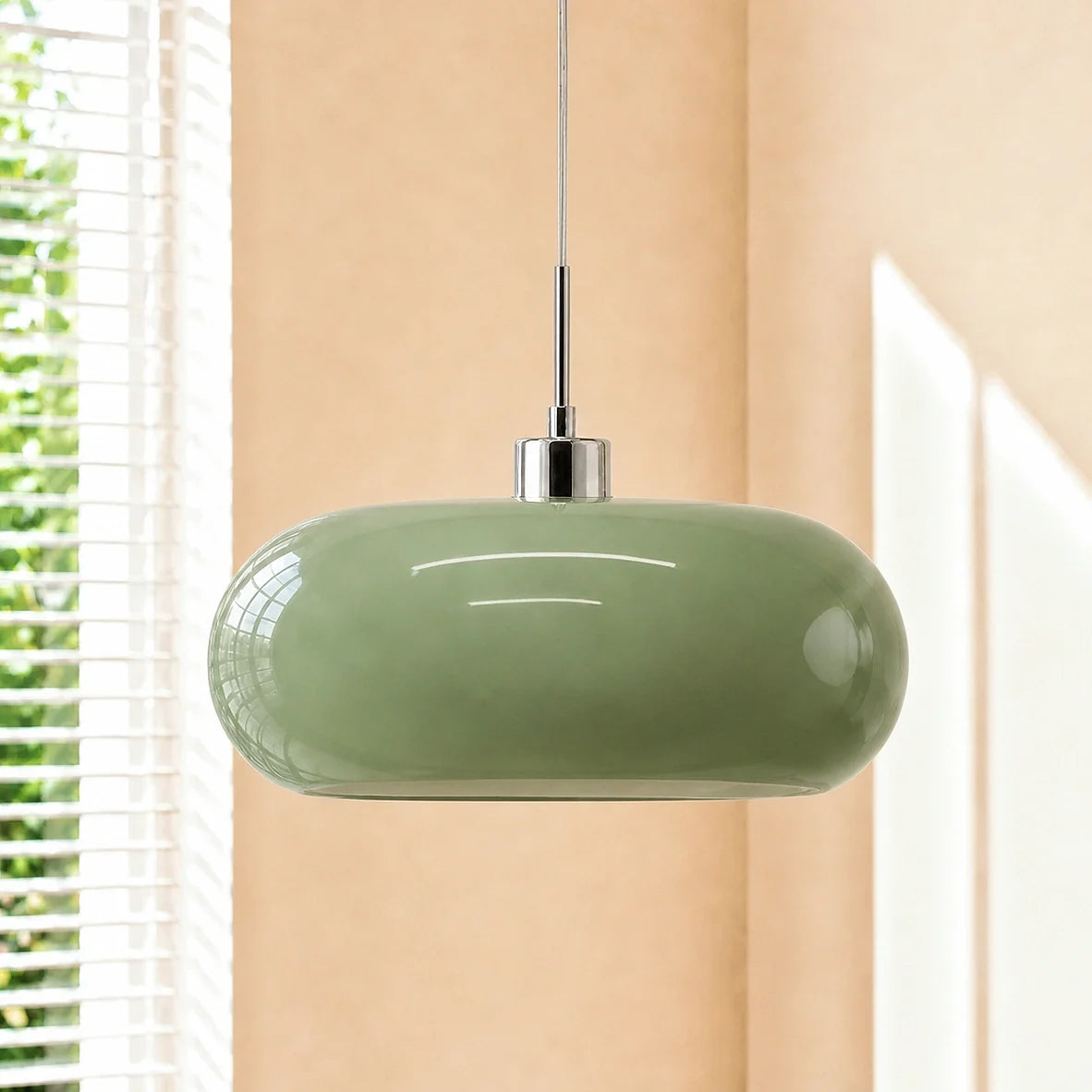 Green oval glass pendant light with chrome cap by a window