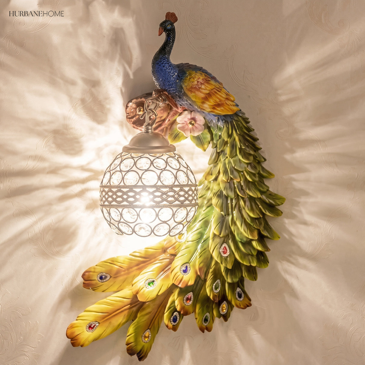 Green and yellow peacock wall sconce with a glowing faceted crystal ball shade