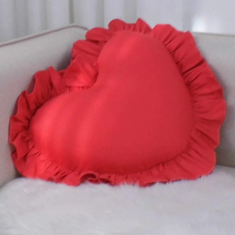 Decorative seating accessory featuring heart shaped pillow with ruffle edge