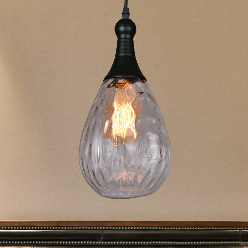 Clear teardrop pendant lit warm on an ochre wall above dark panelling