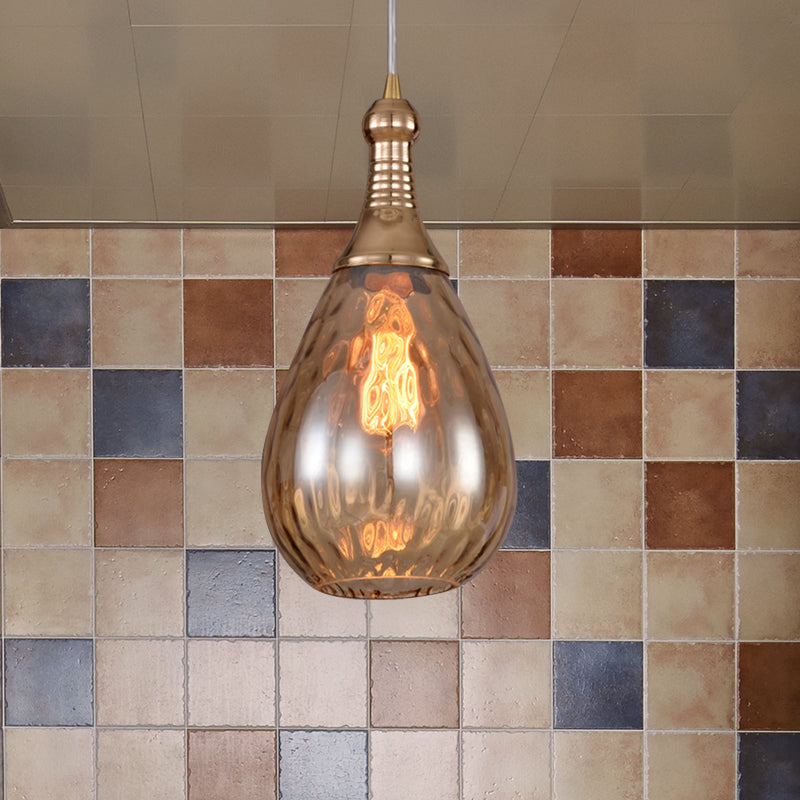 Amber teardrop pendant in front of a coloured mosaic tile wall