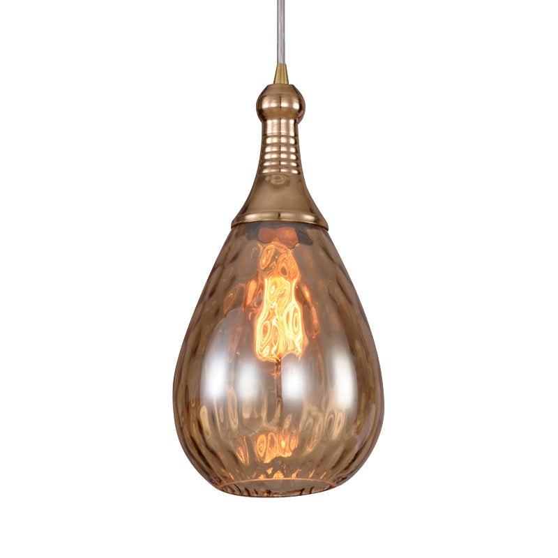 Brass capped teardrop pendant with a lit filament bulb on white