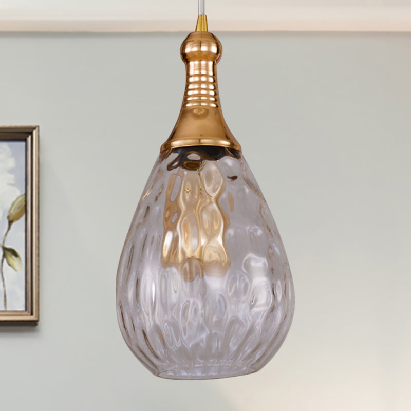 Clear teardrop pendant beside framed art and a small potted plant