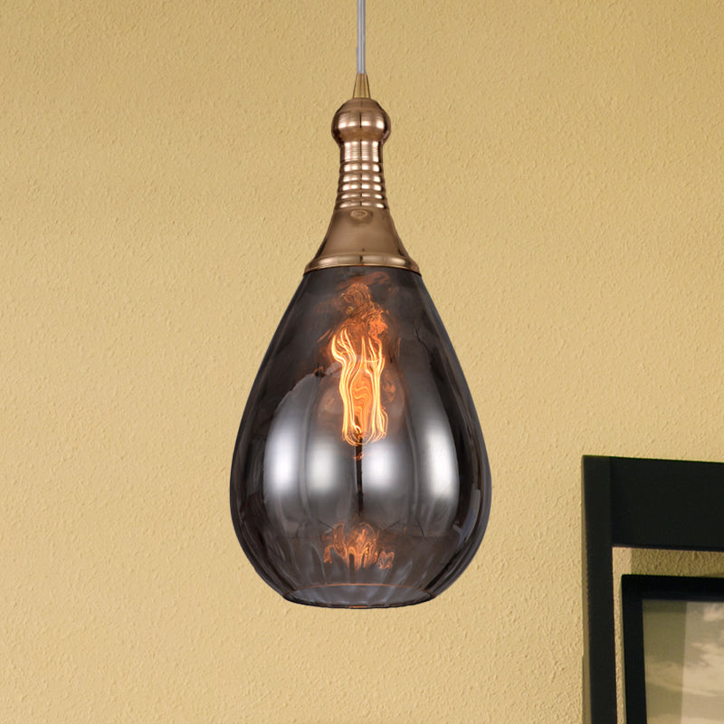 Smoke teardrop pendant lit against a warm yellow wall beside a frame