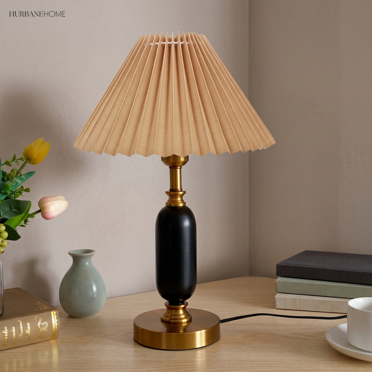 Khaki pleated shade lamp with black column and brass foot on a desk