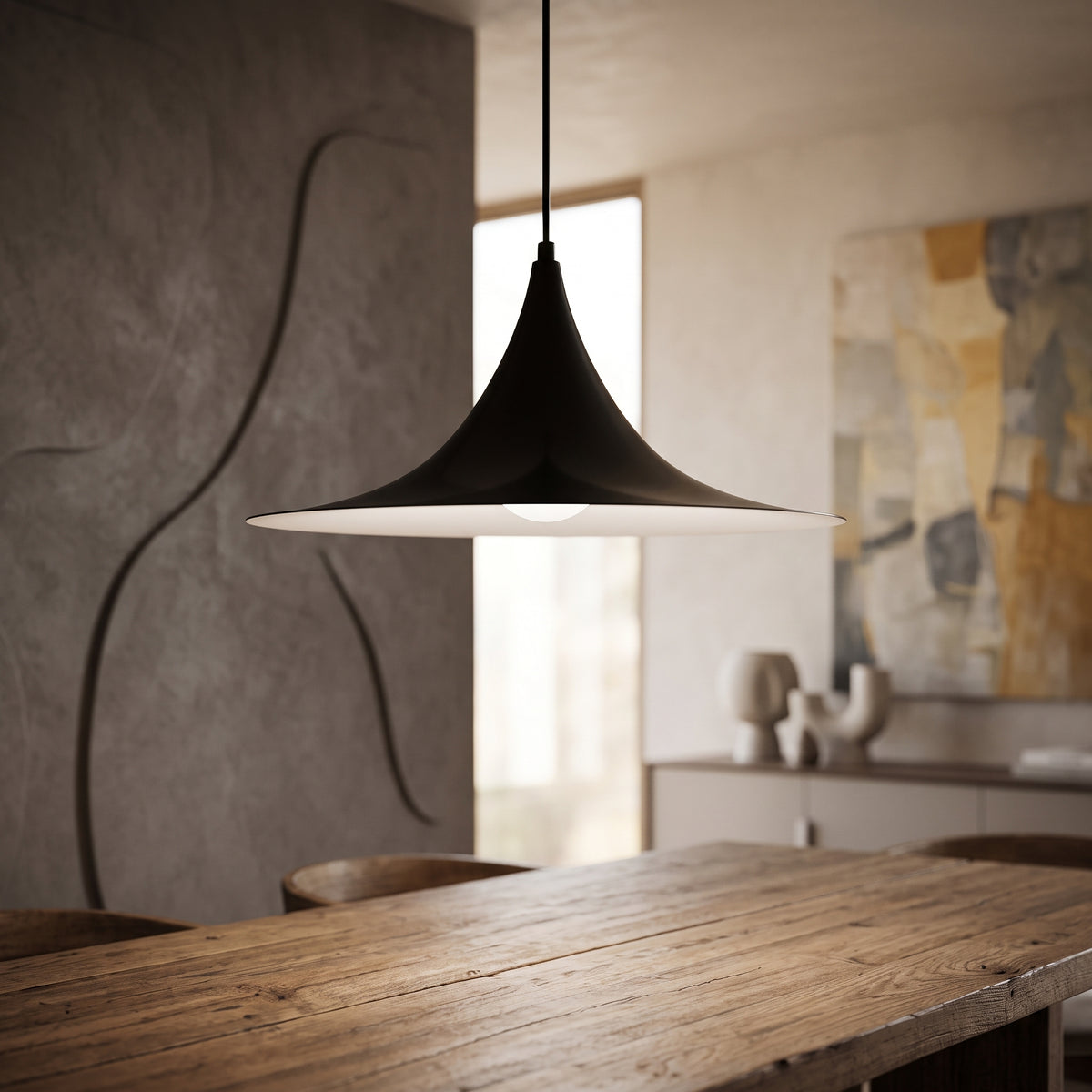 Black flared metal pendant lit above a rustic timber dining table