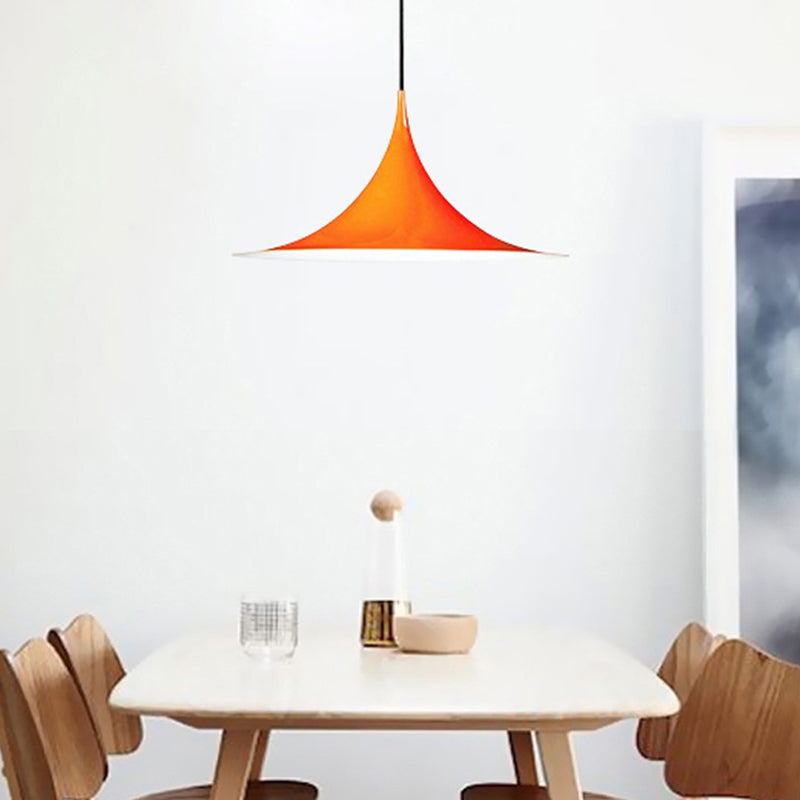 Orange flared pendant lit above a white dining table and chairs
