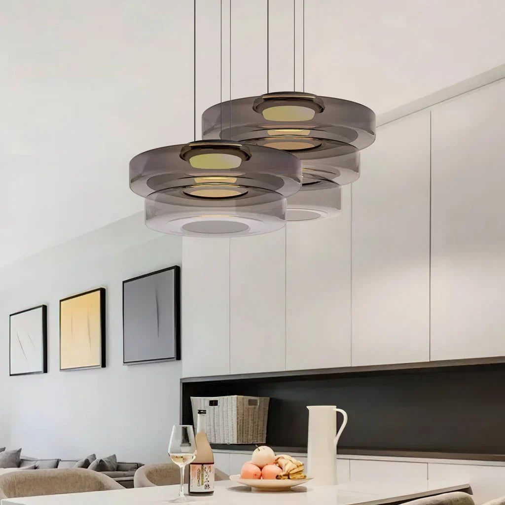 Cluster of smoke grey three-layer glass pendants over a white kitchen island