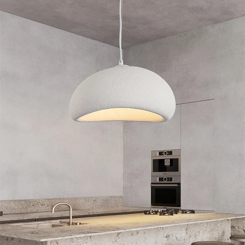 White dome pendant lit above a stone kitchen bench and tap