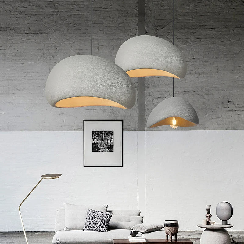 Three white dome pendants lit above a sofa in a bright room