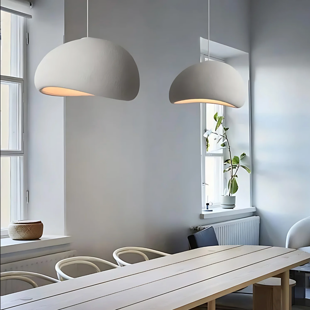 Two white dome pendants lit above a long timber table