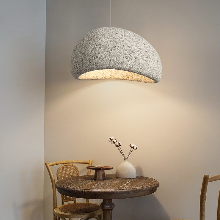 Grey dome pendant lit above a table with a chair and vase