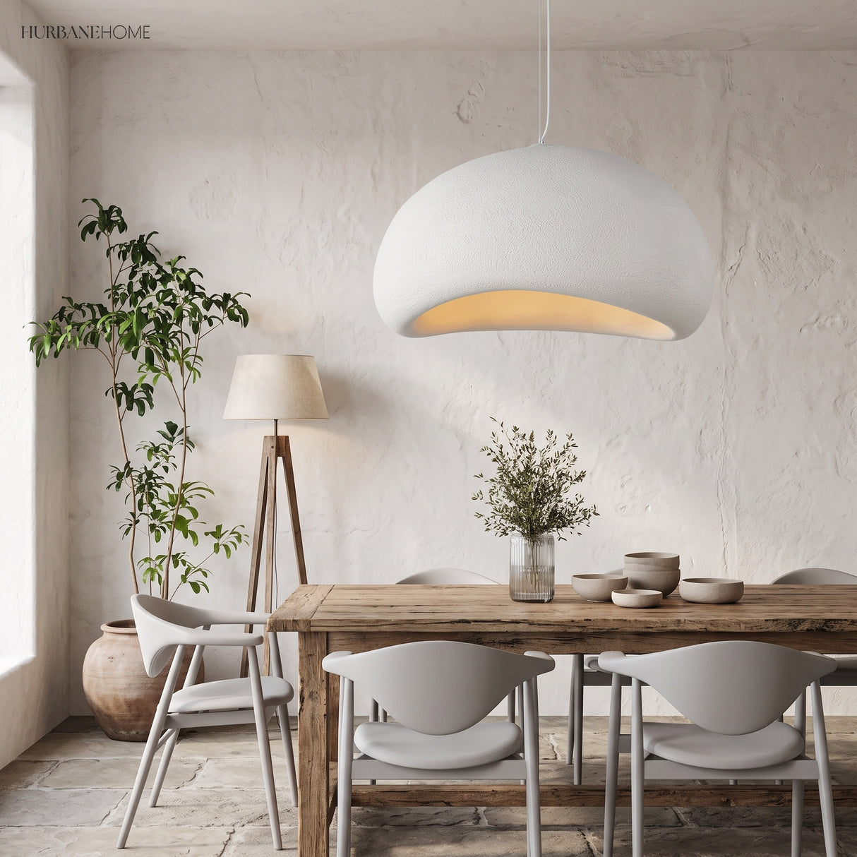 White wabi sabi pendant lit above a wooden dining table and chairs
