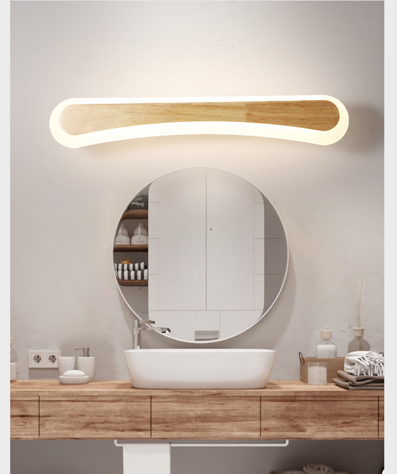 Curved wood vanity light lit above a round mirror and timber top