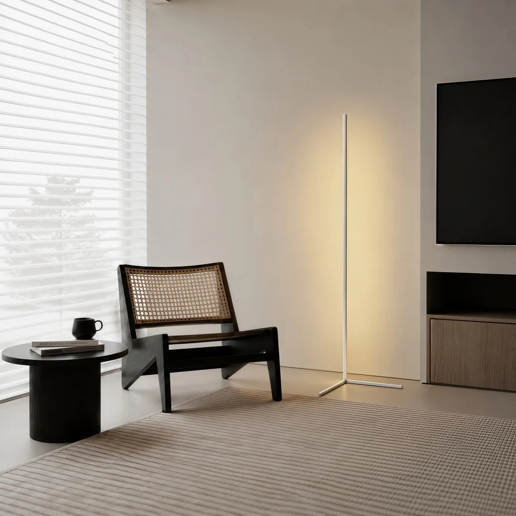 White corner floor lamp glowing beside a cane chair and wall mounted television
