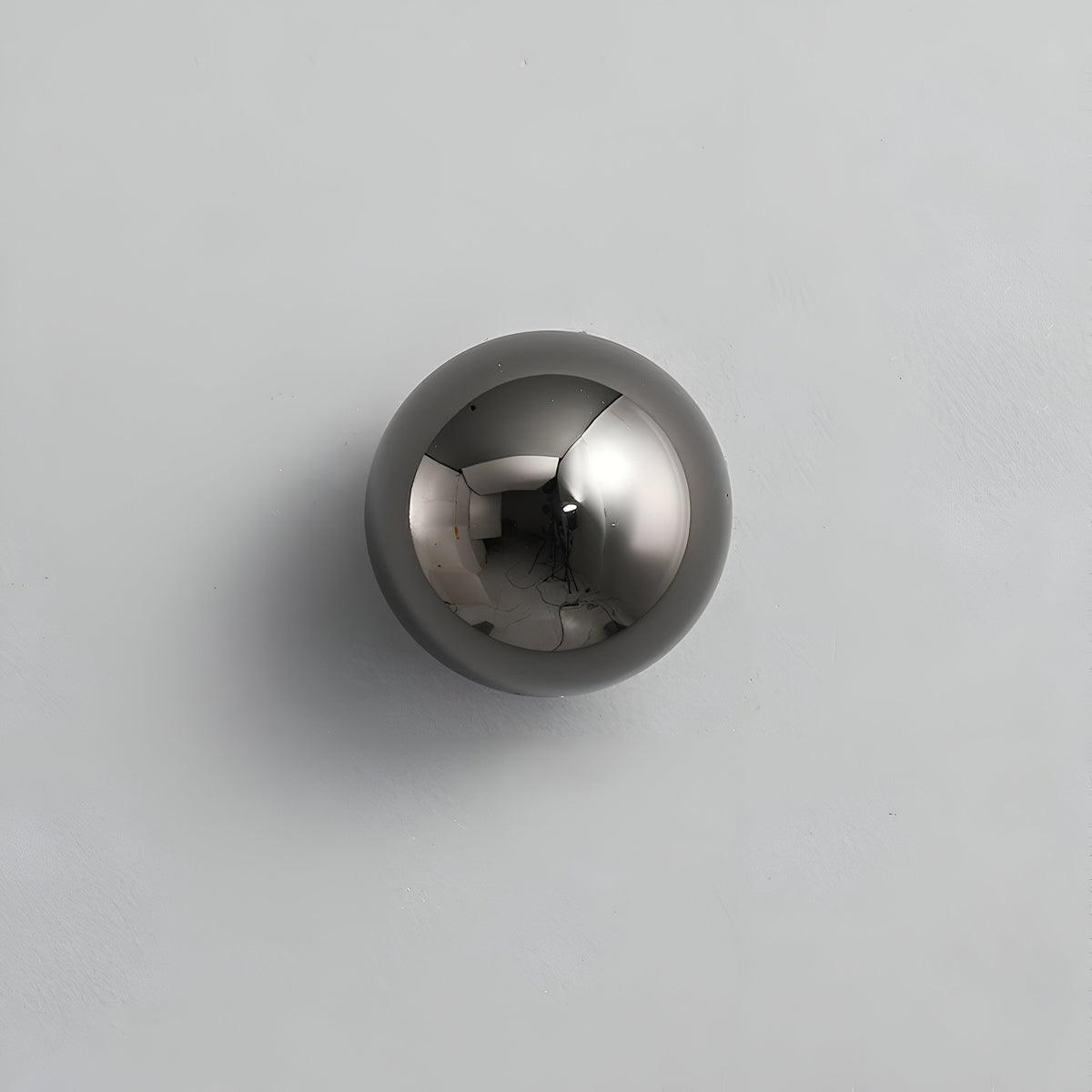 Black dome sconce lit on a white wall beside a dark headboard
