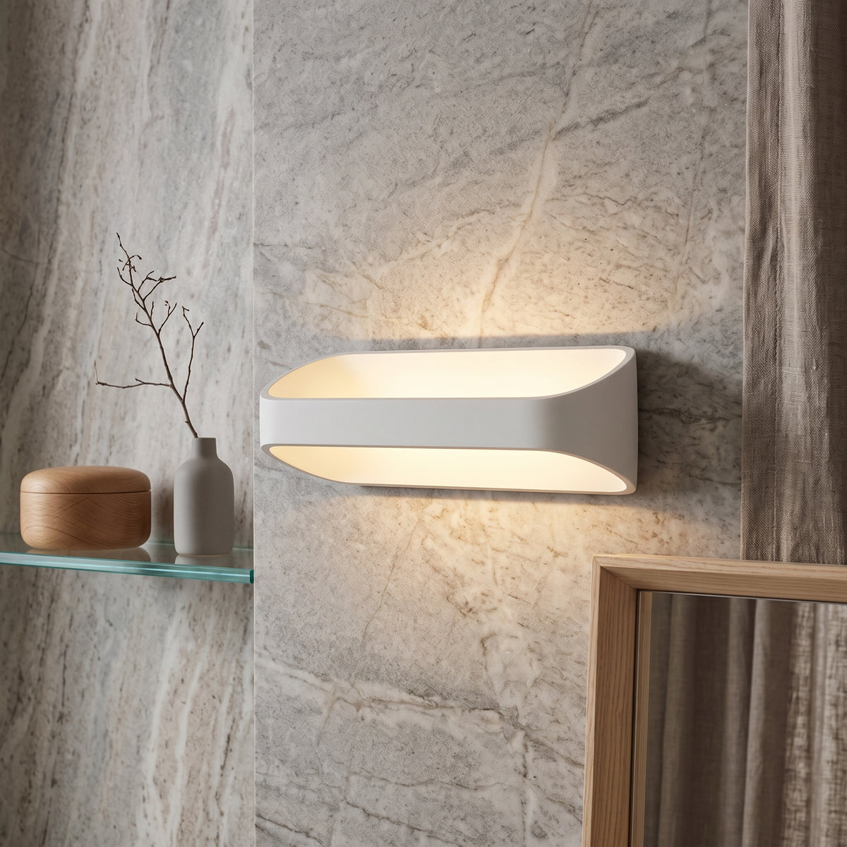 White oval sconce lighting a marble wall above and below