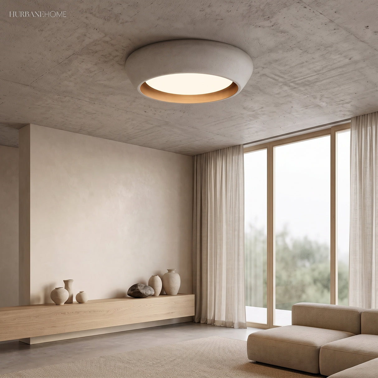 Light grey cement flush mount ceiling light glowing warmly in a minimalist living room