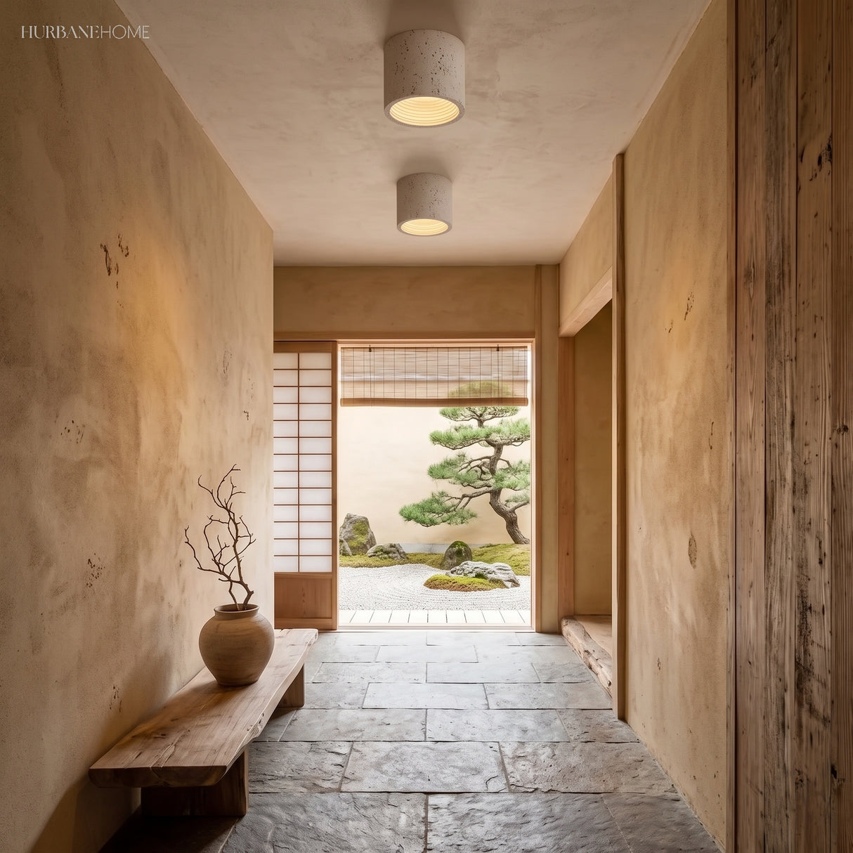 Two cream cylinder ceiling lights lighting a Japandi stone hallway with bonsai