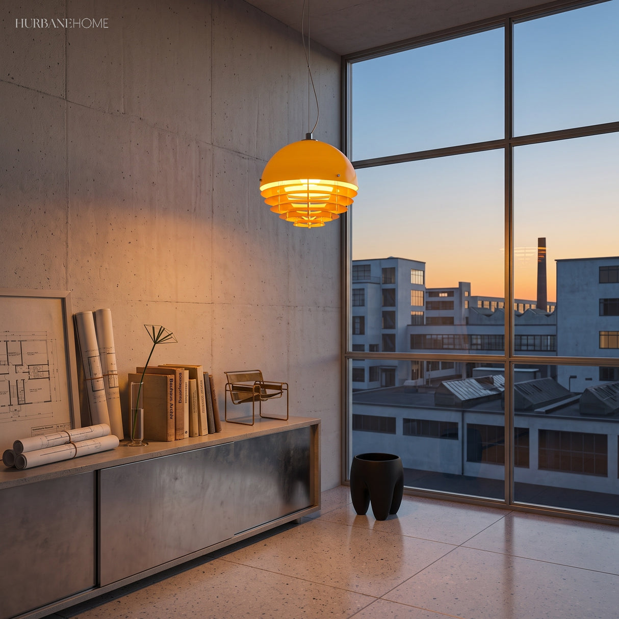 Lit orange dome pendant in a concrete room with framed architectural drawings
