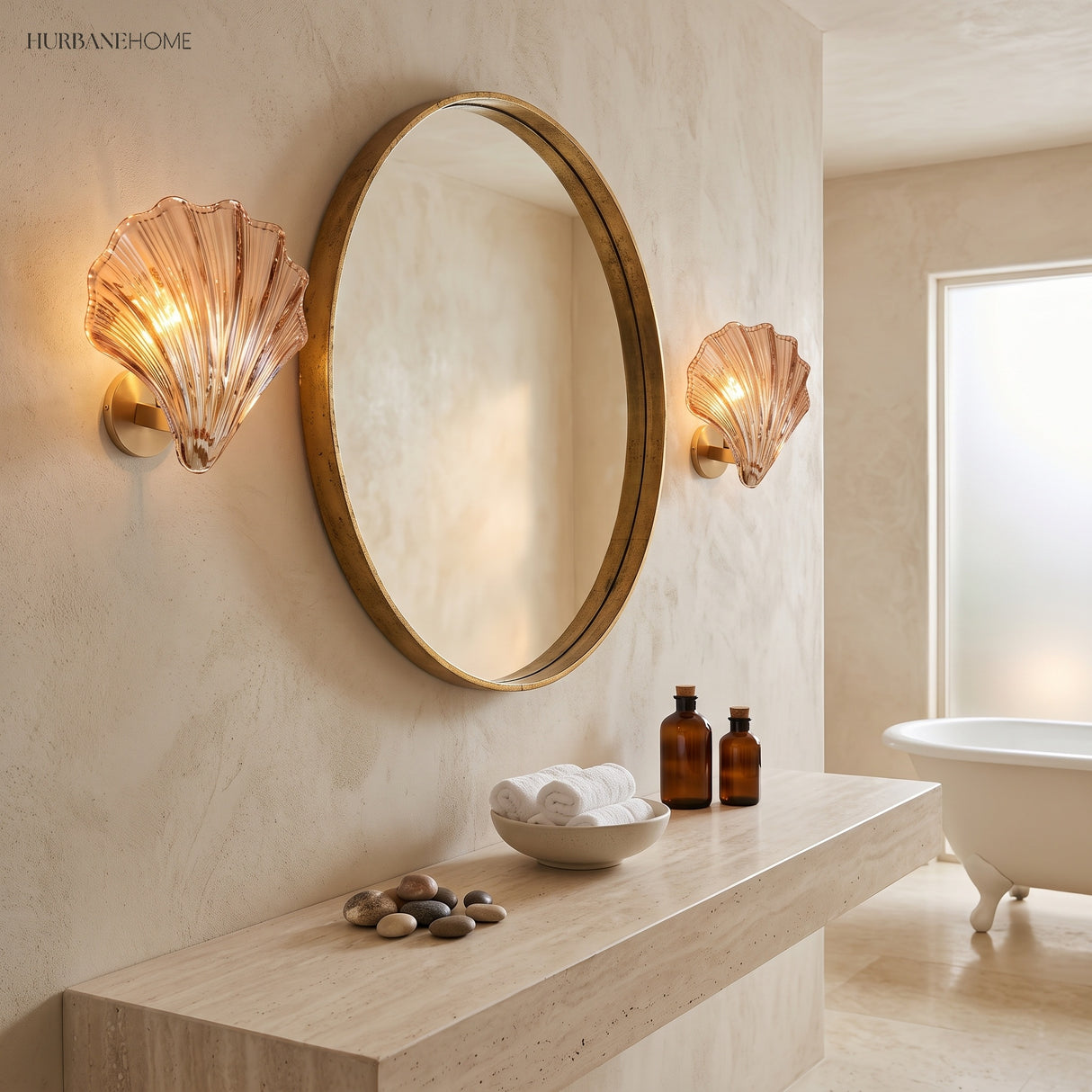 Two brass shell wall sconces flanking a round gold mirror in a warm bathroom