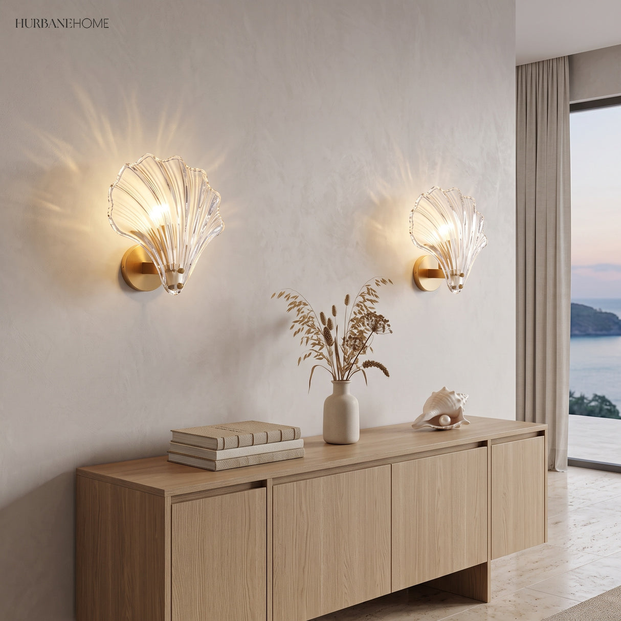 Two clear glass shell sconces on a plaster wall above a light oak sideboard