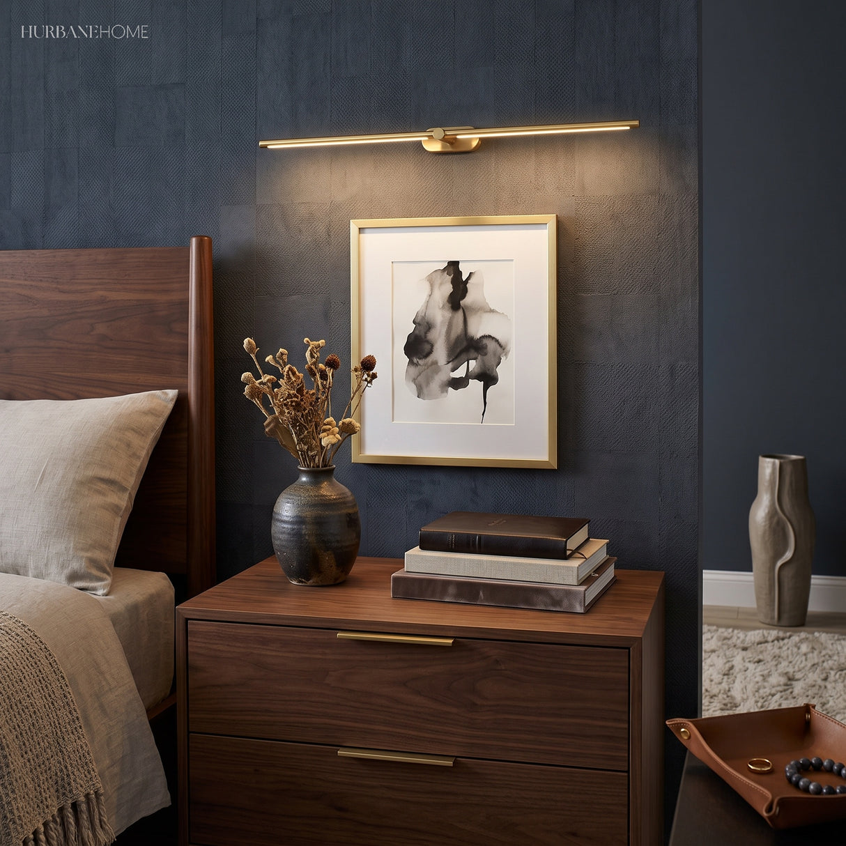 Gold linear LED sconce above framed art and a walnut nightstand
