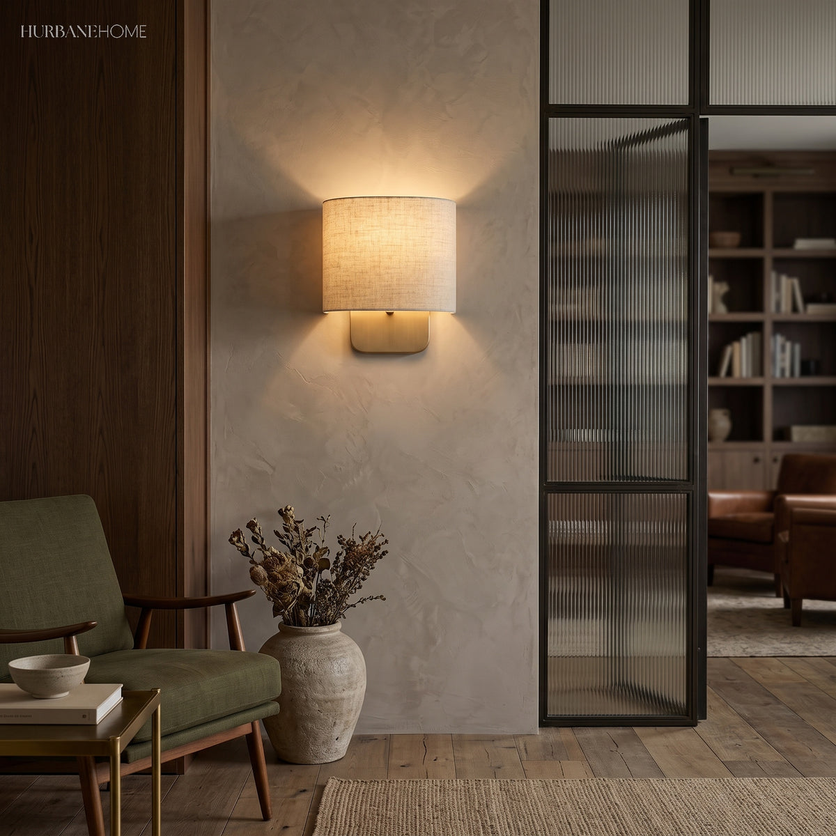 Linen shade wall sconce beside a fluted glass door and green chair