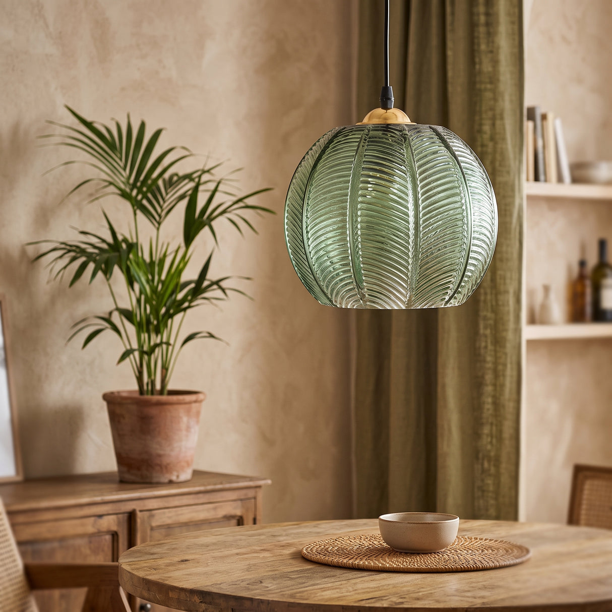 Green textured glass globe pendant with palm leaf ribbing and wooden cap in a boho dining room