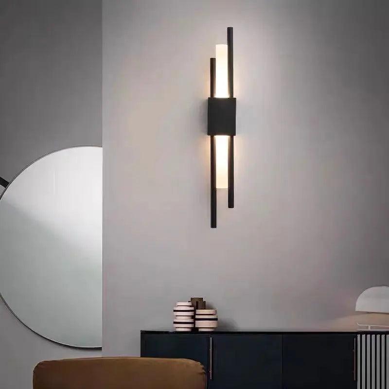 Black linear sconce lit on a pale wall above a slatted cabinet