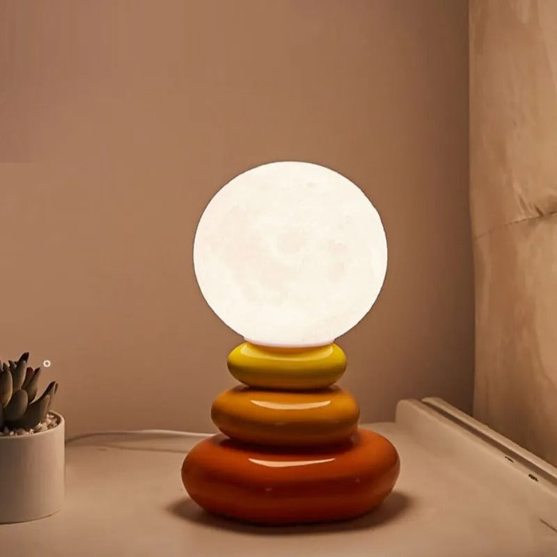 Orange and yellow stacked lamp lit against a warm pink wall