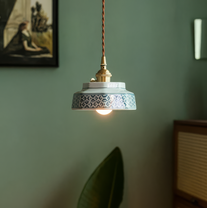 Pale green stepped ceramic pendant lit against a green wall