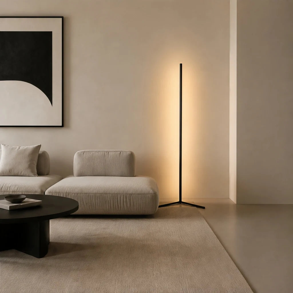 Black corner floor lamp lighting a sofa nook below a bold framed print