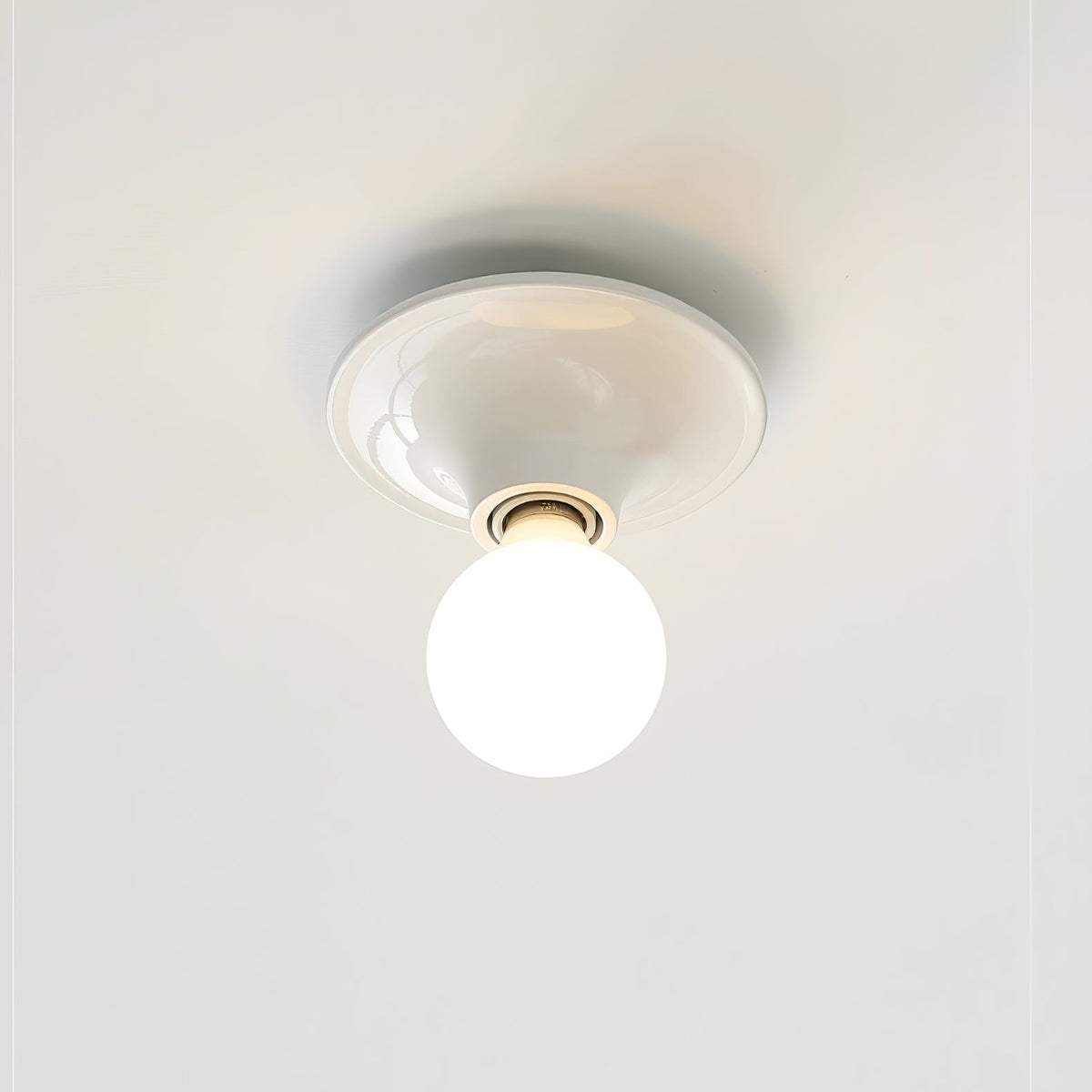 White disc ceiling light mounted flush with a globe bulb pointing down
