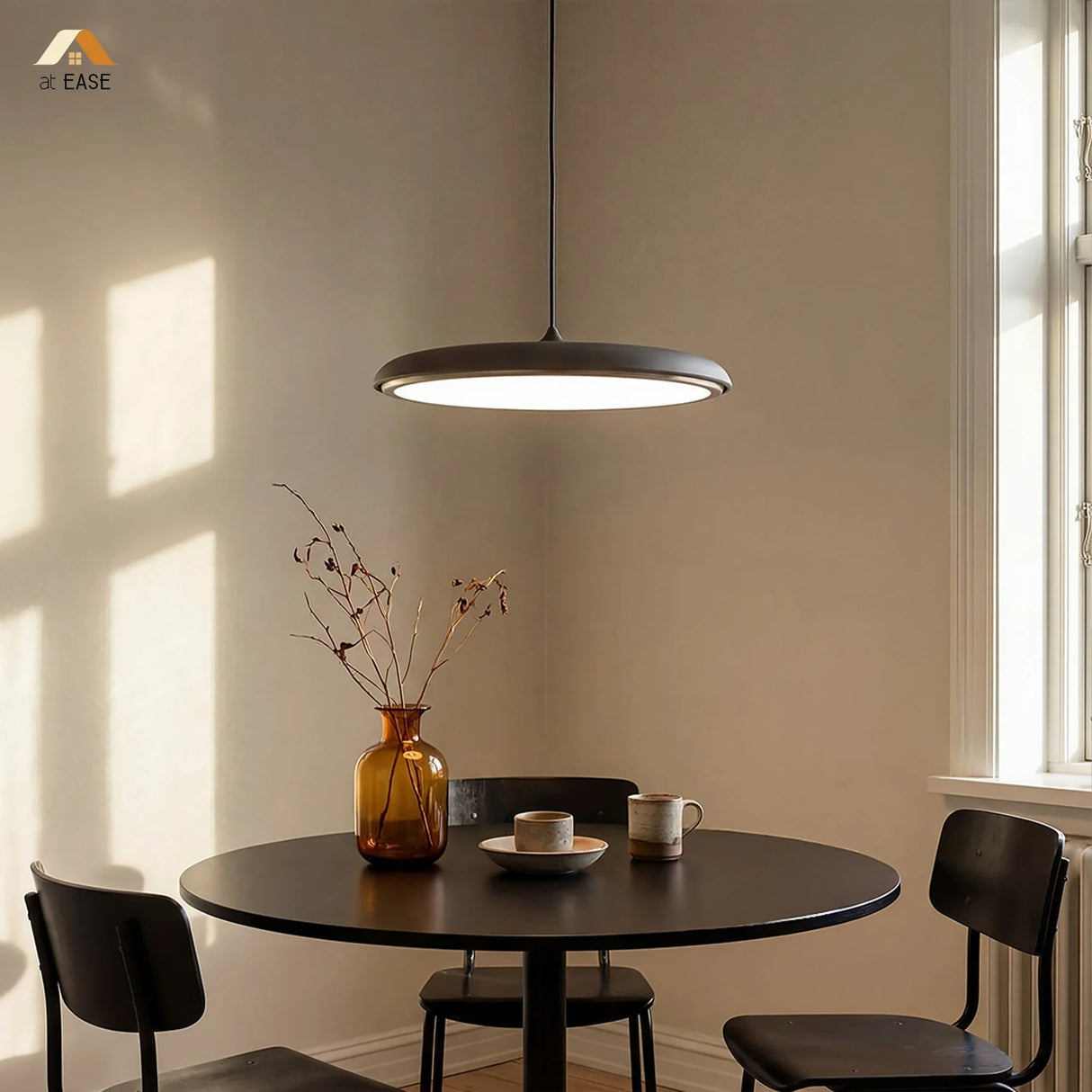 Grey disc pendant light shown against a soft neutral studio background