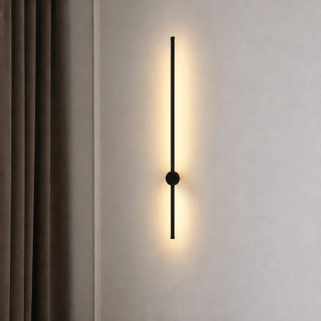 Vertical black linear LED wall light beside a soft beige curtain