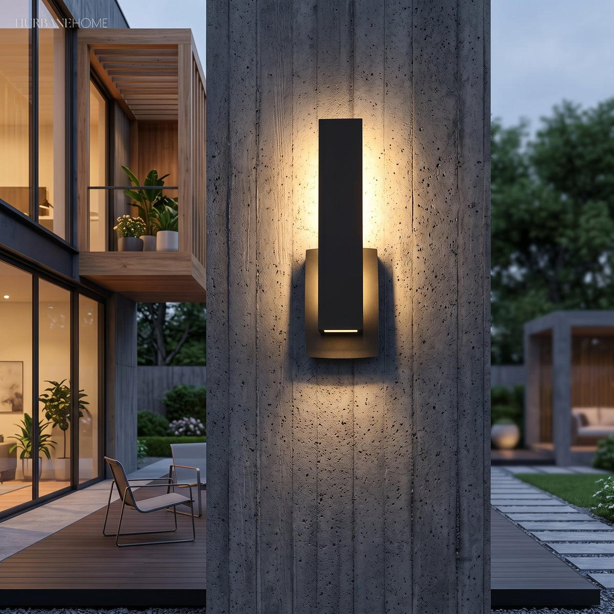 Rectangular outdoor sconce glowing beside a concrete pillar and planting