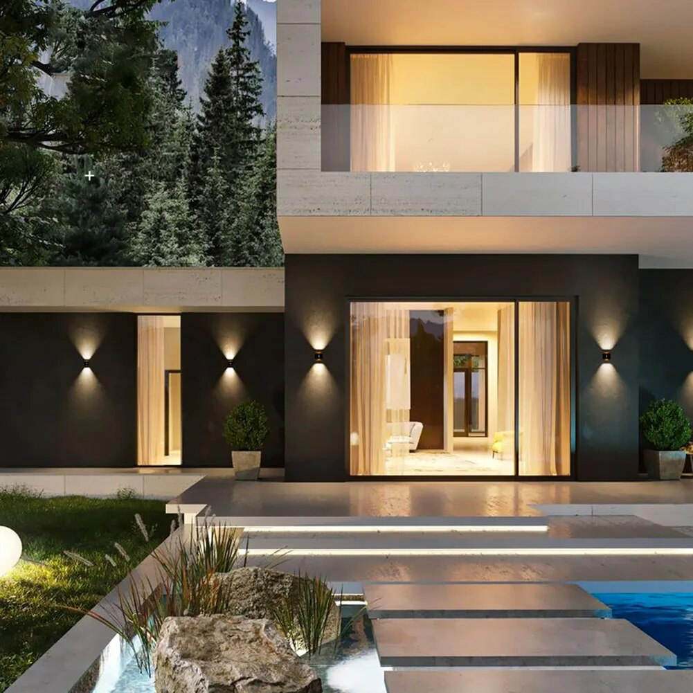 Up down wall sconces lit along a modern house front by a pool