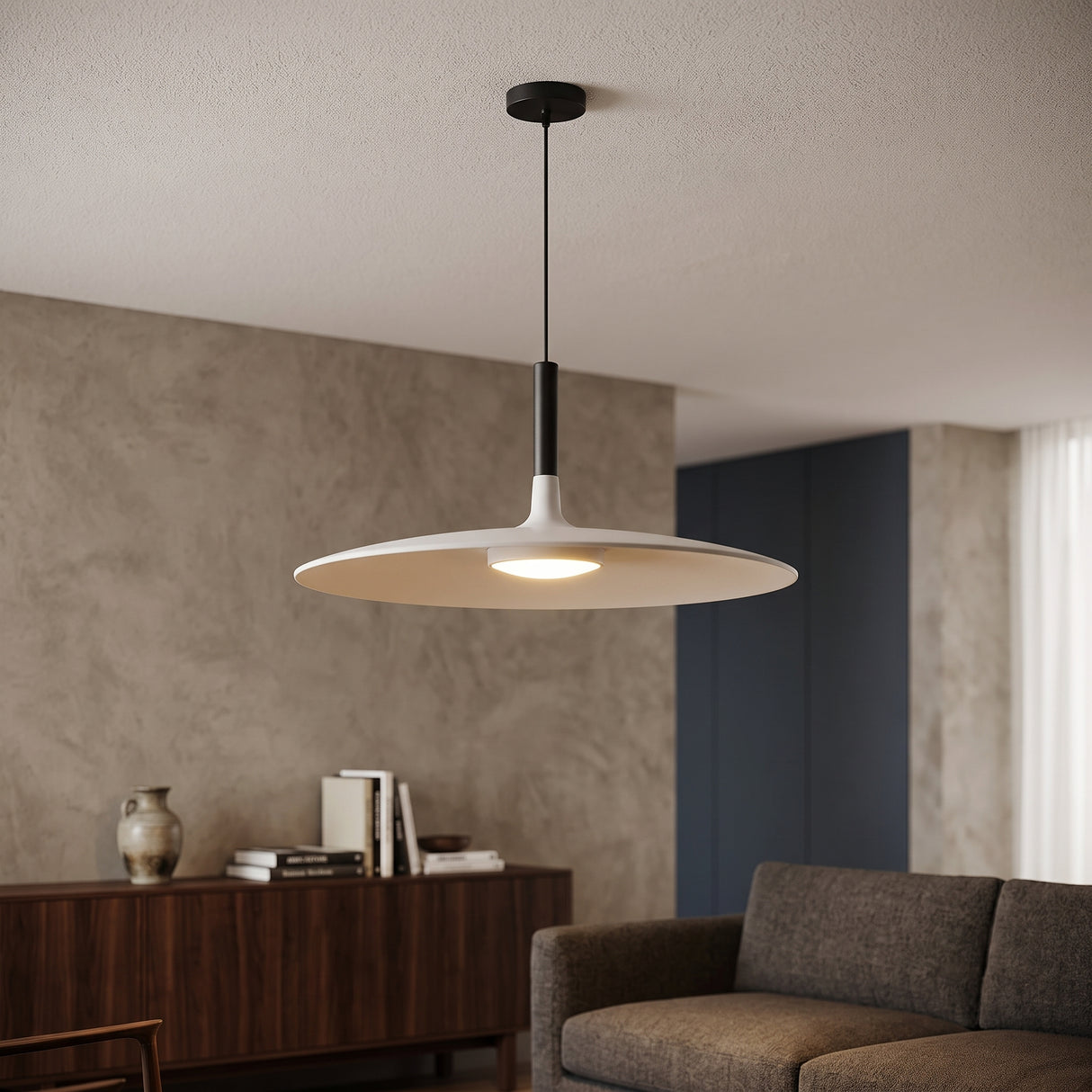 White saucer pendant lit above a sideboard beside a grey sofa