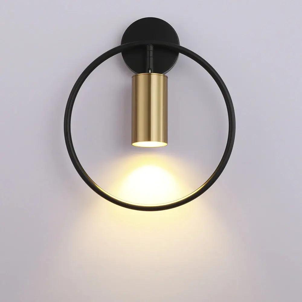 Black ring paired with a gold cylinder spot on a pale wall
