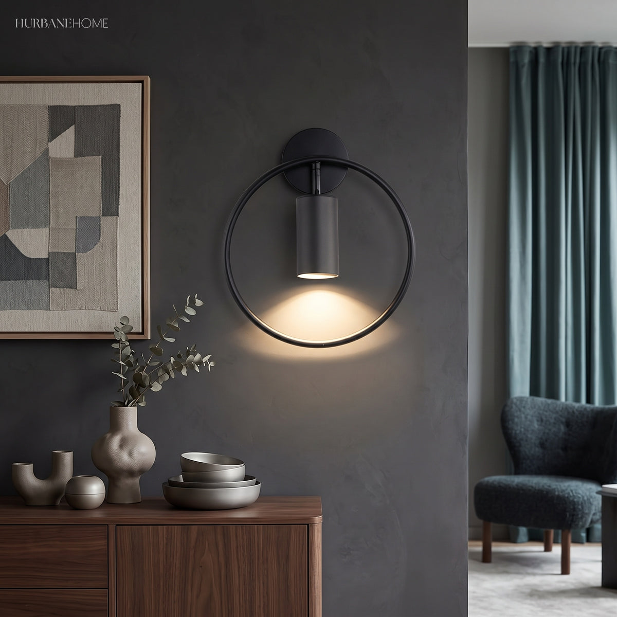 Black ring sconce lit on a dark wall above a wooden sideboard
