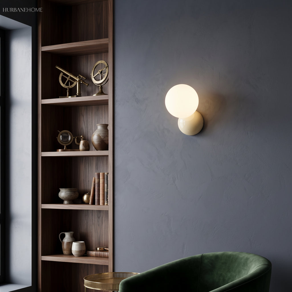 Wall sconce lit against a deep blue wall next to tall shelving and a velvet chair