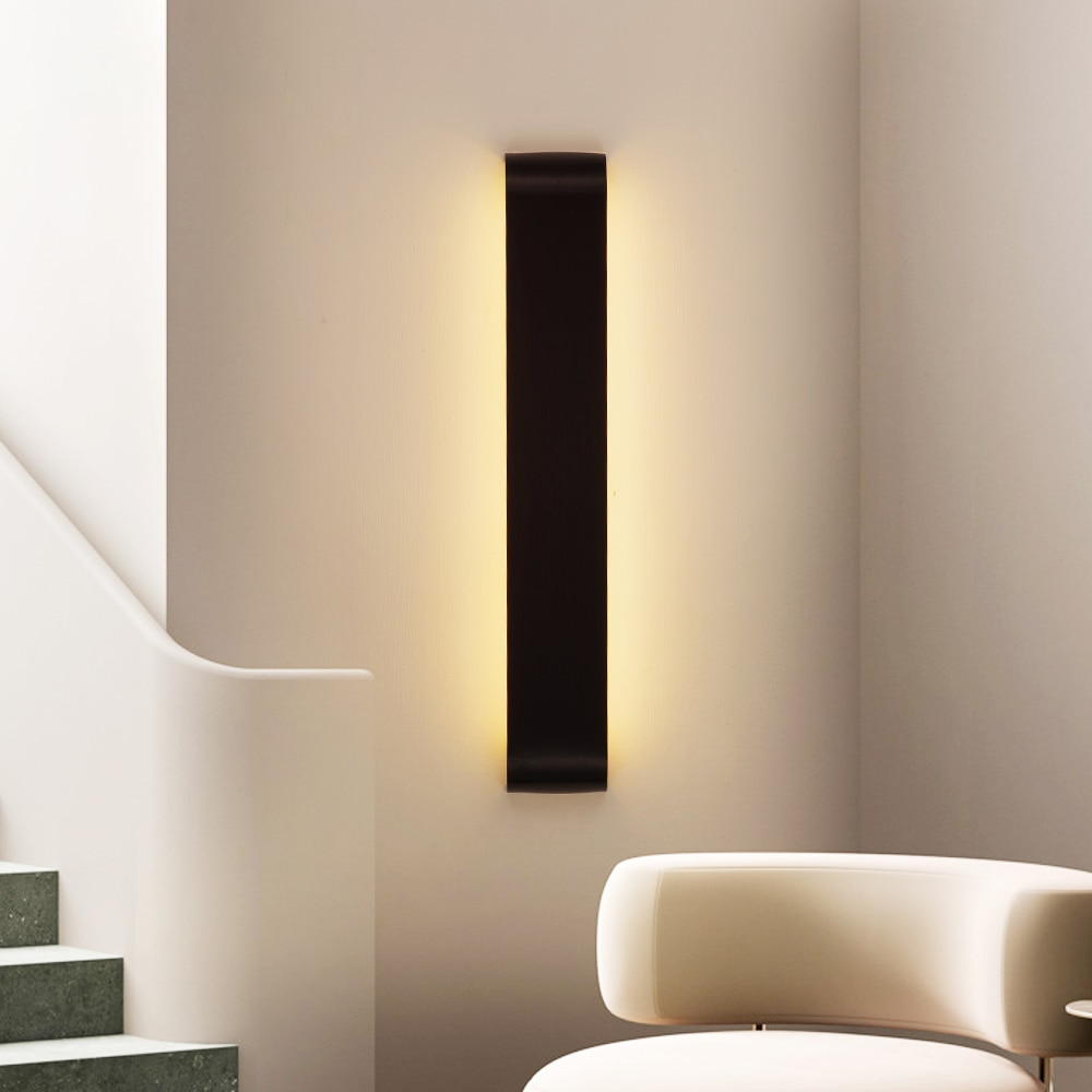Black linear wall sconce mounted vertically on a pale stair wall