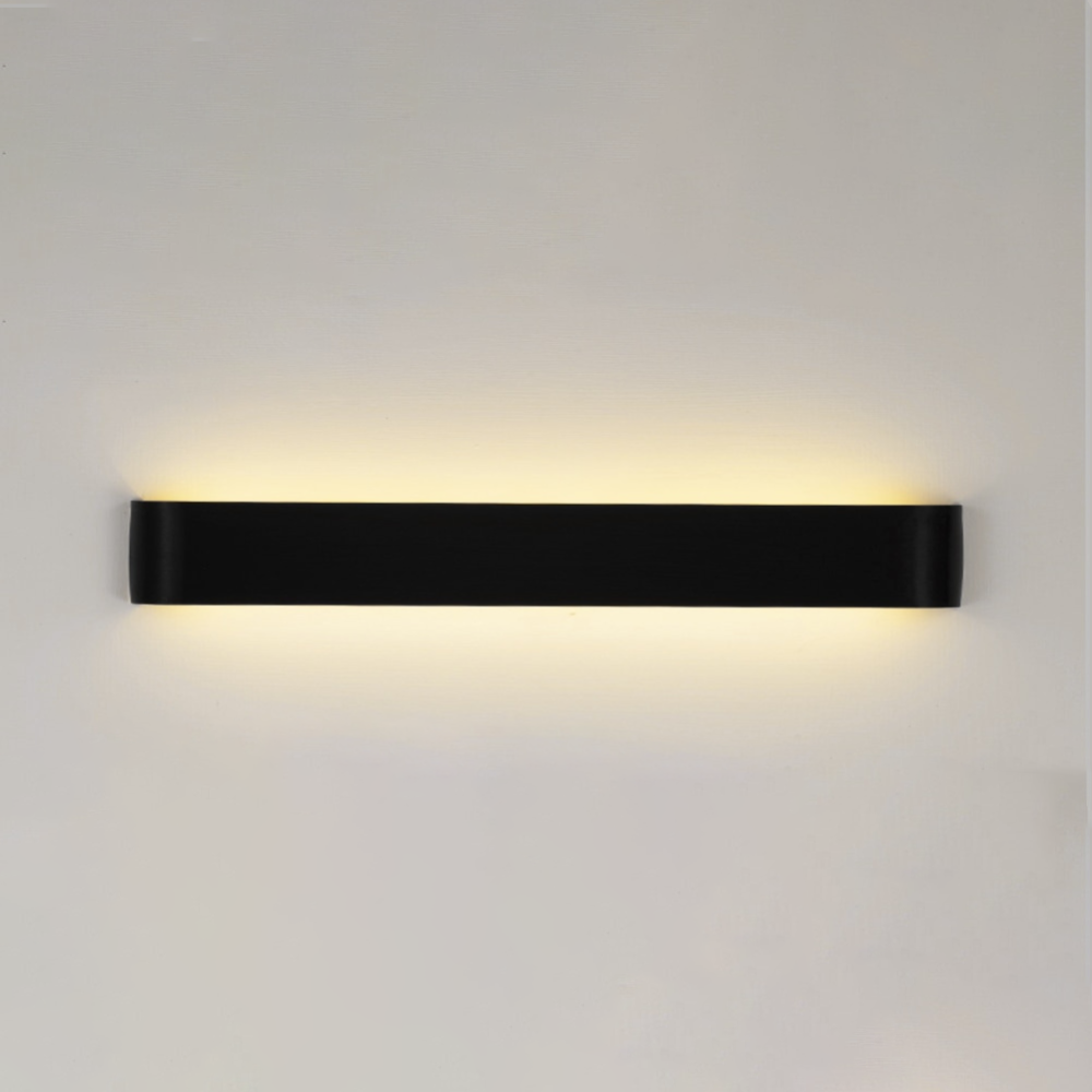 Black linear wall sconce lit on a plain white wall